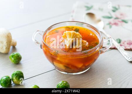 vegetable soup with Brussels sprouts and cauliflower, in a glass plate on a wooden table Stock Photo