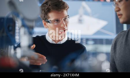 Asian Development Engineer Student Brainstorming with his Caucasian Classmate in a High Tech Research Laboratory with Modern Equipment. Education and Innovative Technologies Concept Stock Photo