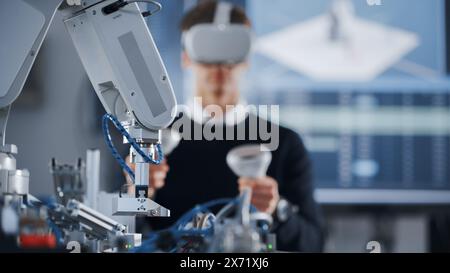 Student Developer Writing Code and Testing Interface of Bionic Hand. Engineer Wearing Virtual Reality Headset and Using Controllers at Modern University of Technology. Virtual Reality Concept. Stock Photo