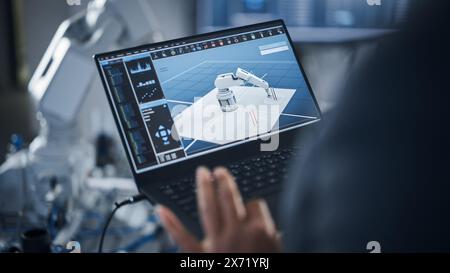 Black Female Engineer Using Laptop for Programming Robotic Arm At the Futuristic Advanced Factory. New Generation Technology in Automatic Manufacturing Industry Concept. Cropped View. Stock Photo