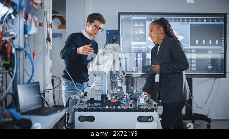 Futuristic Design of AI Robot Hand. Black Engineer Telling About Innovative Robot Arm to Students or Start-uppers. Advanced Robotics Technology for Factory Working Concept. Slow Motion. Stock Photo