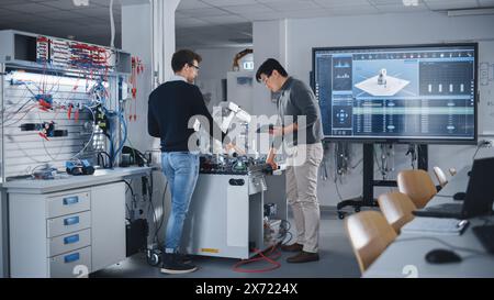 Curious Students are Working Together on Modification of Functions of High-Tech Mechanical Arm for Engineering Project at School During Workshop. Computer Science Education Concept. Stock Photo