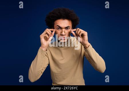 Photo portrait of attractive young man touch specs skeptical dressed stylish beige clothes isolated on dark blue color background Stock Photo