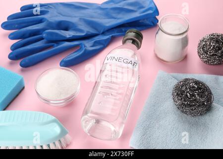 Eco friendly natural cleaners. Vinegar in bottle, soda, brushes and gloves on pink background Stock Photo