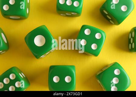 Many green game dices on yellow background, flat lay Stock Photo