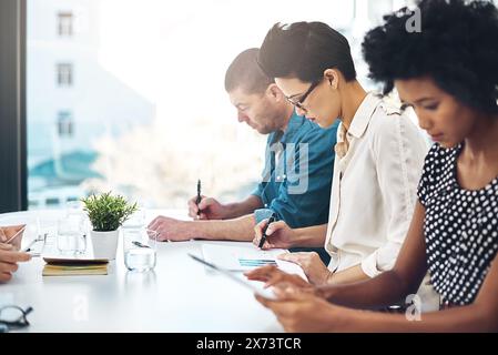 Business people, meeting and writing notes in office for collaboration, brainstorming or sharing ideas. Teamwork, employees or colleagues working Stock Photo