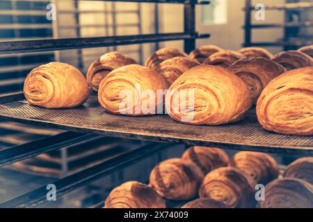 Freshly baked croissants on a shelf cart in a bakery, vertical Stock Photo