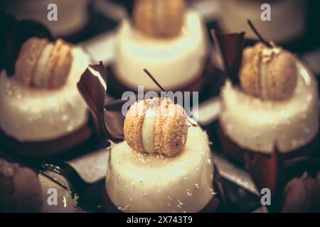 Tartlet with creamy glaze, decorated with a macaraon, coconut flakes and chocolate, close-up Stock Photo
