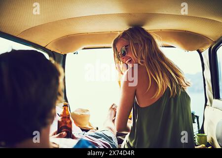 Travel, couple and car boot for relax and drink, happy and vehicle for road trip and vacation. Smile, sunset and date for man and female person in Stock Photo
