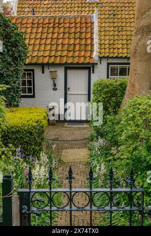 Small cosy house with red tiled roof and well-kept garden, old houses with green gardens in a small village, nes, ameland, the netherlands Stock Photo