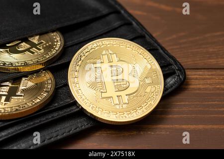 Cryptocurrency bitcoin gold coins in wallet on wooden background. Stock Photo