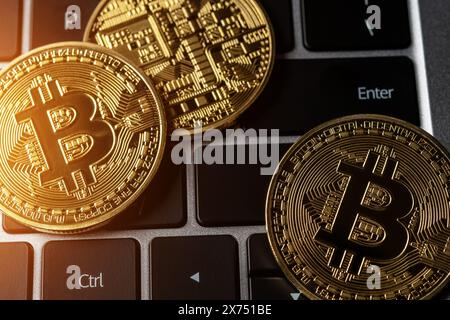 Close up view of Bitcoin gold coins on laptop keyboard. Stock Photo