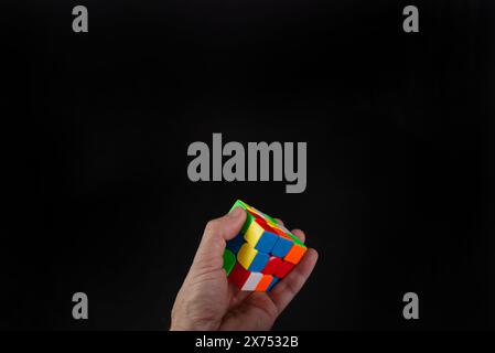 Salvador, Bahia, Brazil - May 15, 2024: Rubiks cube in a persons hands, portrait, black background. Man holding Rubiks cube and playing Stock Photo