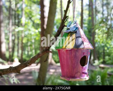 Collection of birdhouses made by children and placed on fallen trees in the forest. Stock Photo