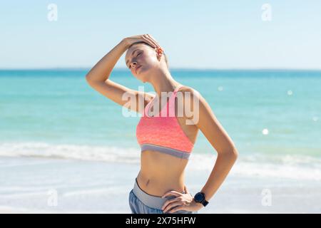 At beach, Caucasian young woman standing, hand on forehead Stock Photo