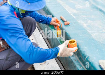 Worker apply rubber adhesive on plastic canvas for gasket edge of waste water dome. Stock Photo