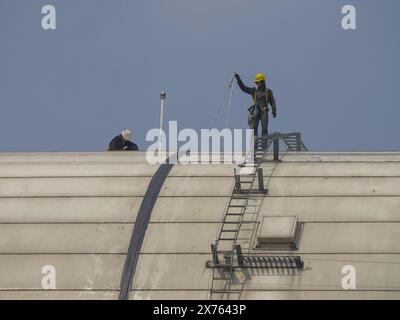 Jakarta, Indonesia - may 06, 2024 : workers on top of the building do not use personal protection Stock Photo