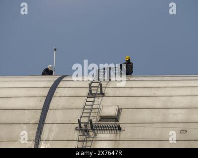 Jakarta, Indonesia - may 06, 2024 : workers on top of the building do not use personal protection Stock Photo