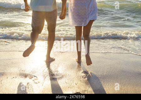 At beach, biracial couple holding hands, walking Stock Photo