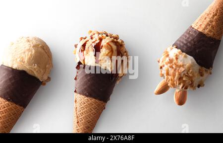Detail of three ice cream cones of various flavors with chocolate cones on white background. Stock Photo