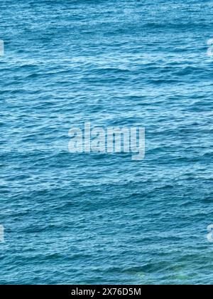 Vertical dark blue sea ripples background. Sea surface wrinkled with the wind. Water backdrop. Aquatic texture. Aesthetic mobile phone wallpaper. Stock Photo