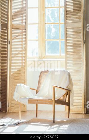 Wooden armchair with plaid against windows with shutters , room composition and sunlight . High quality photo Stock Photo