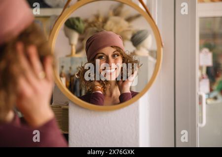 Happy Fashion Designer Adjusting Headband While Looking in Mirror Stock Photo