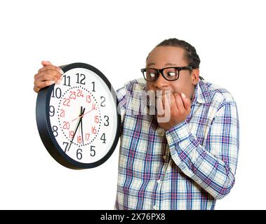 Stressed young man running out of time looking at wall clock Stock Photo