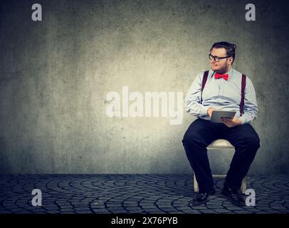 job seeker young man waiting for interview meeting sitting on a chair looking aside Stock Photo