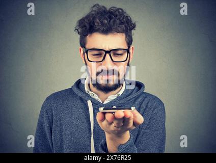 Portrait of a young man using a mobile phone and asking a question to an artificial intelligence assistant Stock Photo