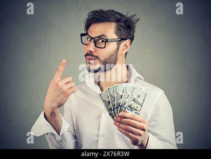 Portrait of a sly businessman with hundred dollar bills giving one piece of advice Stock Photo