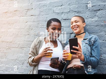 Online, video and friends with phone watch post on social media in city on coffee break or share gossip. Happy, people or laughing at joke on web Stock Photo