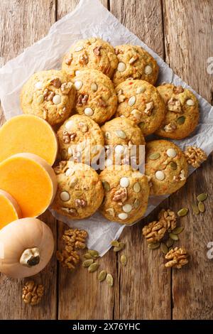 Healthy gluten-free pumpkin cookies with walnuts and seeds close-up on parchment on a wooden table. Vertical top view from above Stock Photo