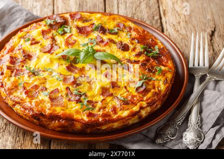 Frittata with chicken, cheese, eggs, bacon and herbs close-up in a plate on the table. Horizontal Stock Photo