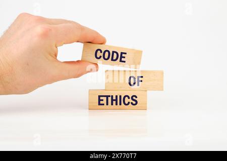 Organizational concept. CODE OF ETHICS is written on wooden blocks it is laid out by hand on wooden bars Stock Photo