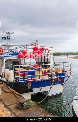 Large Fishing Boat Moored at Wells-next-the-Sea on an Overcast day in May with Red Pink Buoys and Fish Boxes Stock Photo