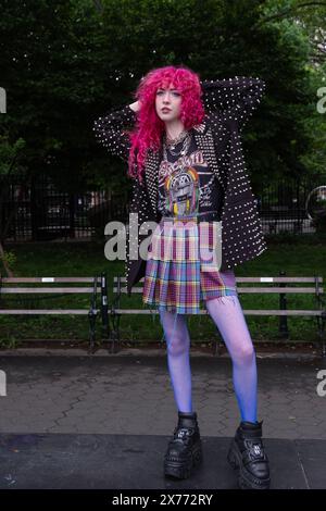 A beautiful woman with bright pinkish red hair and her own personal style. Posing in Washington Square Park in Greenwich Village, New York in 2024. Stock Photo