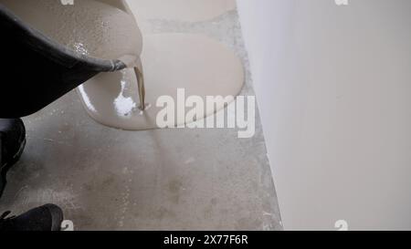 Workers pour self-leveling floor. Pouring Self-Leveling Floors. Self-Leveling Floors On A Large Area, A Worker. Self-leveling epoxy. Leveling with a Stock Photo