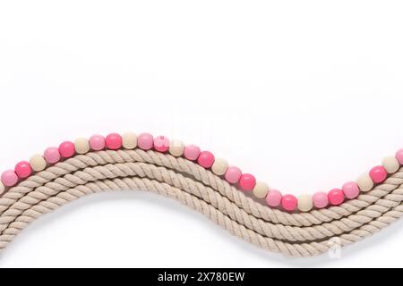 wavy thick textured rope and smooth wooden bead border in shades of off white and pink on a white background Stock Photo