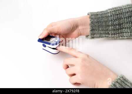 Woman using fingertip pulse oximeter on white background, close up. Stock Photo