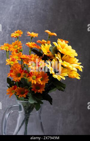 Bouquet yellow and orange flowers in jug on dark background Stock Photo