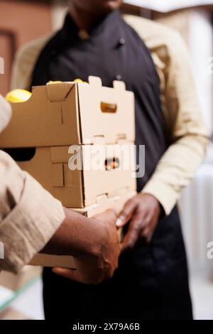 Male owner sells harvested, organic produce in eco friendly grocery store. Customers can choose from a variety of vegetables and fruits, all locally sourced and packaged in reusable containers. Stock Photo