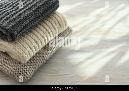 Stack of knitted scarfs on wooden table, space for text Stock Photo