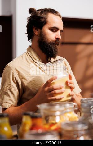 Man in zero waste store taking time to analyze bulk products, making sure they contain no allergens. Customer thoroughly checking food items are safe in environmentally conscious local shop Stock Photo