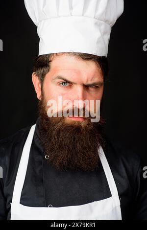 Closeup portrait of serious male chef cook or baker. Professional chef man in cook uniform, hat and apron. Cooking and food preparation. Handsome Stock Photo