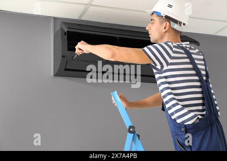 Male technician repairing air conditioner indoors Stock Photo