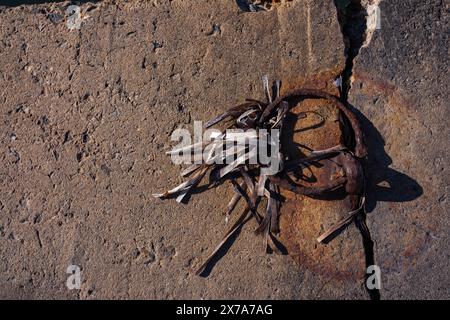 A rusty metal mooring ring has left rusty marks on the concrete in which it is embedded. Remains of dried seaweed hang on the metal. Sea pier, summer, Stock Photo