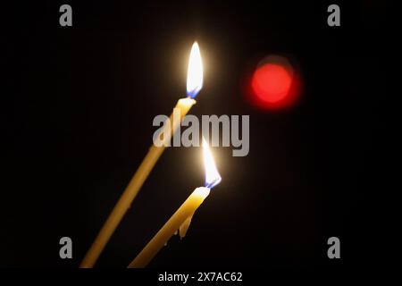 Details with burning candles in the hands of a person during a religious ceremony. Stock Photo