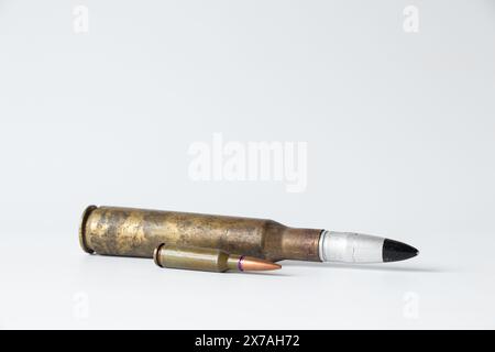 Two bullets, large and small, lie on a white background close-up Stock Photo