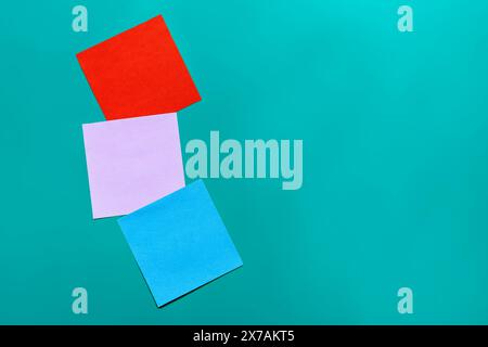 Stack of sticky notes on solid yellow background with blue, lilac, red Stock Photo